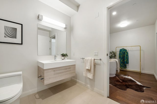 bathroom featuring toilet, baseboards, and vanity