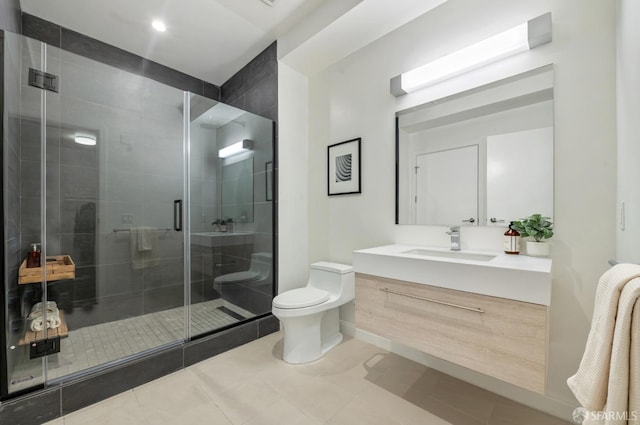 bathroom with toilet, a stall shower, vanity, baseboards, and tile patterned floors