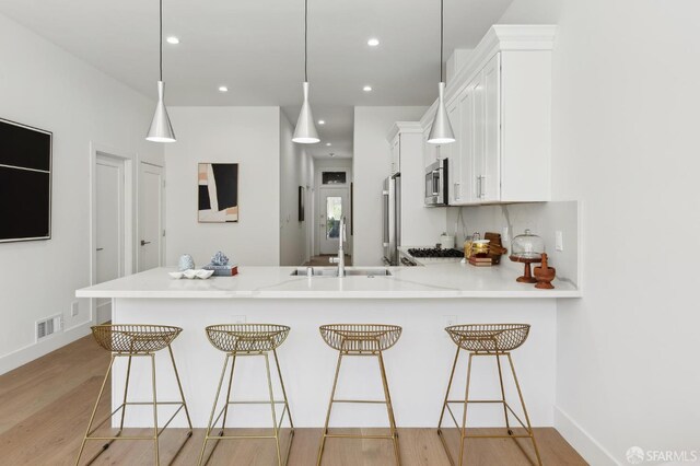 2237 Bryant St Lower, Lower, San Francisco, CA 94110 - kitchen featuring appliances with stainless steel finishes, a sink, light wood-type flooring, light countertops, and white cabinetry