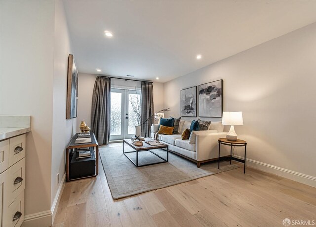 living room featuring light wood-style floors, recessed lighting, french doors, and baseboards