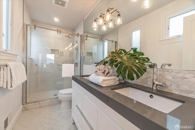 bathroom with toilet, vanity, a shower stall, and visible vents