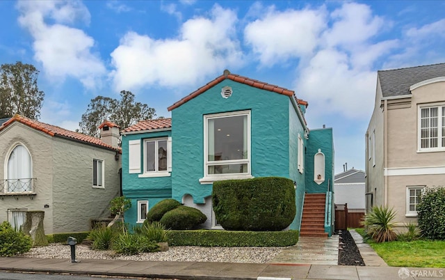 view of front of home with stairway, a tile roof, and stucco siding