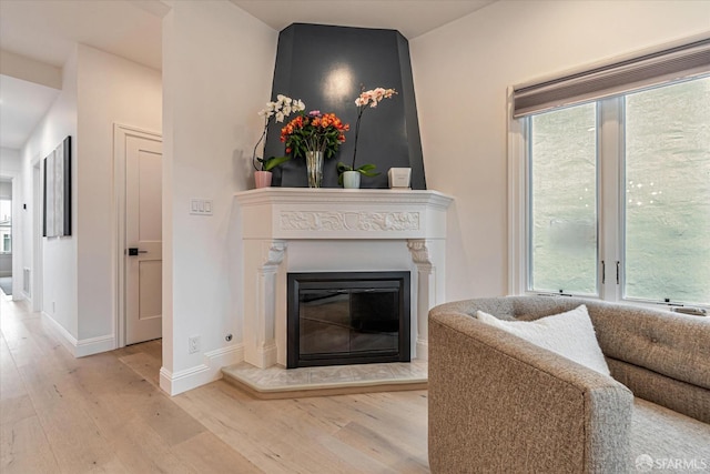 living room with a glass covered fireplace, wood finished floors, and baseboards