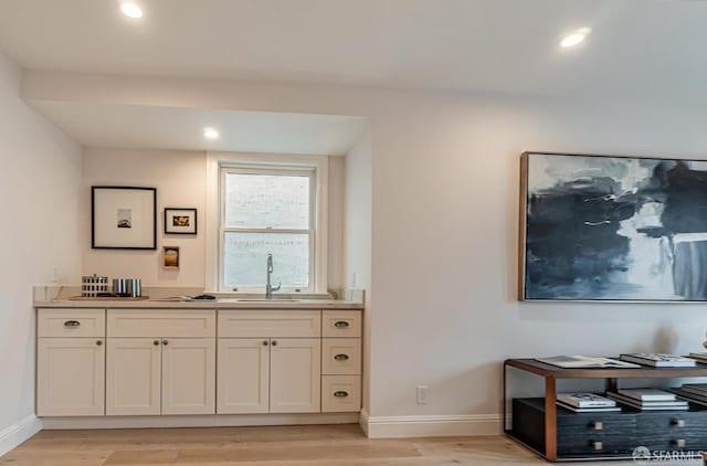 bar with recessed lighting, baseboards, a sink, and light wood finished floors