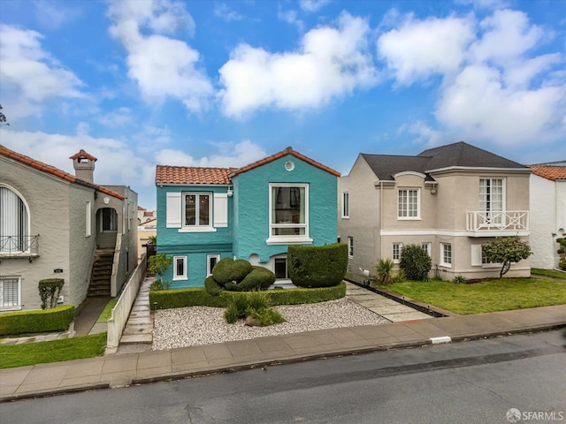 view of front of property with a tiled roof, stairway, and stucco siding