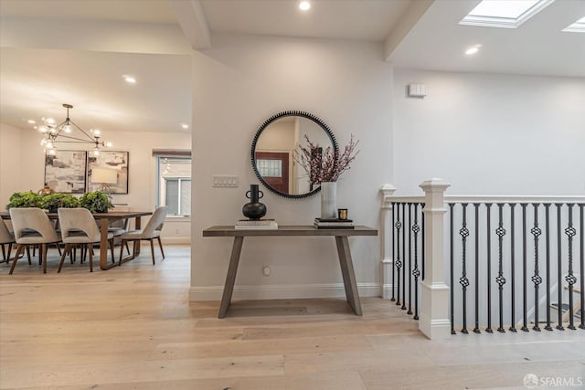 hall with light wood-style floors, baseboards, a notable chandelier, and recessed lighting