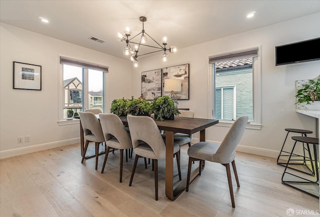 dining room with light wood-type flooring, an inviting chandelier, baseboards, and visible vents