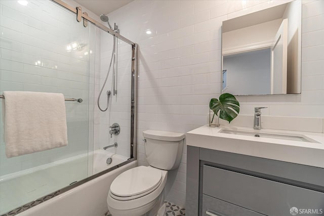 bathroom with toilet, enclosed tub / shower combo, tile walls, and vanity