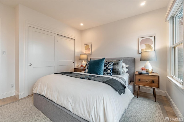 bedroom featuring light wood-style floors, baseboards, a closet, and recessed lighting