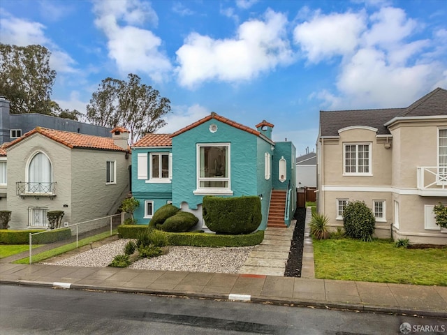 view of front of property with a tile roof, fence, and stucco siding