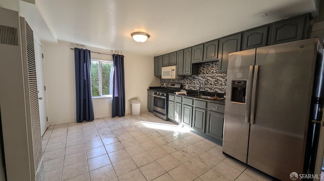 kitchen with backsplash, light tile patterned flooring, sink, and stainless steel appliances