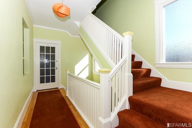 stairway with baseboards, ornamental molding, and wood finished floors