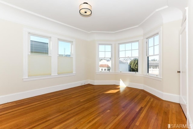 spare room featuring baseboards, ornamental molding, and wood finished floors