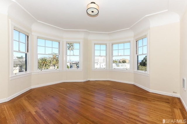 unfurnished room featuring baseboards, visible vents, and wood finished floors