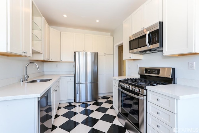 kitchen with open shelves, a sink, light countertops, light floors, and stainless steel appliances