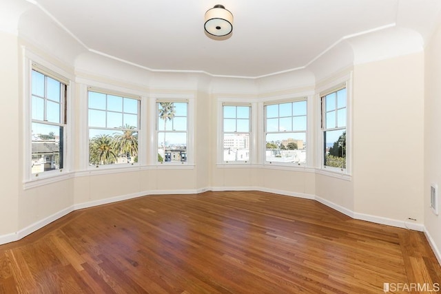 empty room featuring baseboards, visible vents, and wood finished floors