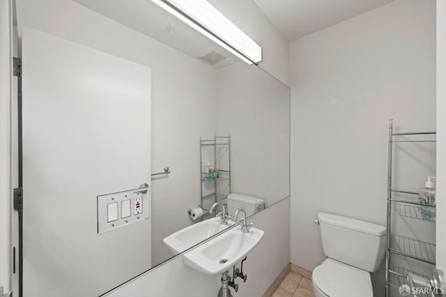 half bathroom featuring tile patterned floors, toilet, and a sink