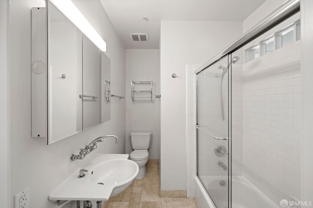 bathroom with baseboards, visible vents, bath / shower combo with glass door, a sink, and toilet