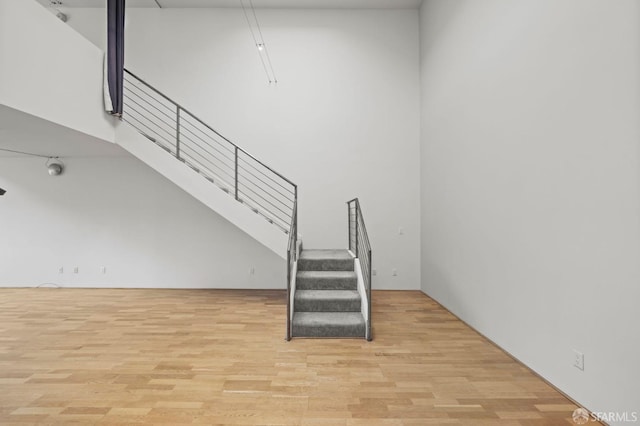 stairway featuring a high ceiling and wood finished floors