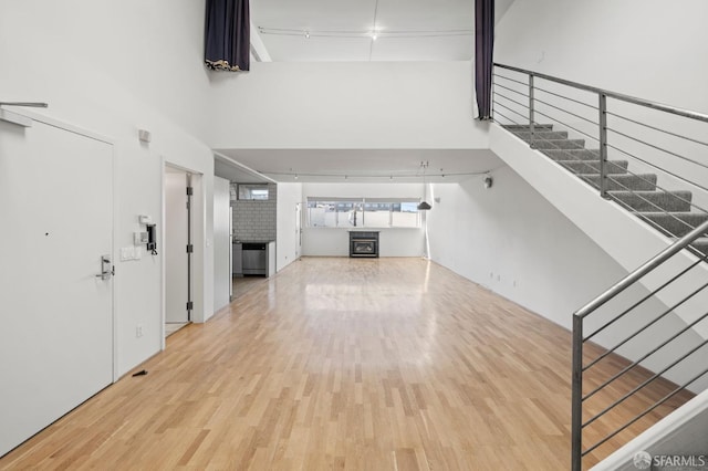 interior space with stairs, track lighting, wood finished floors, and a towering ceiling