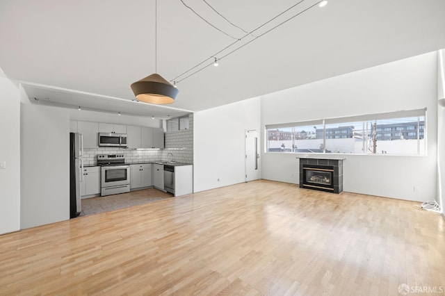 unfurnished living room featuring light wood finished floors, a tiled fireplace, and a sink