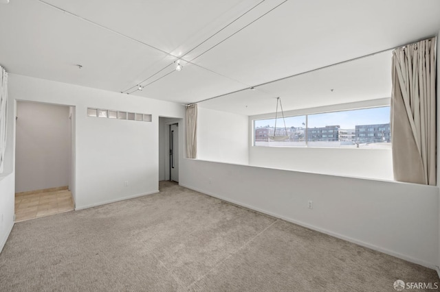 spare room featuring carpet and baseboards