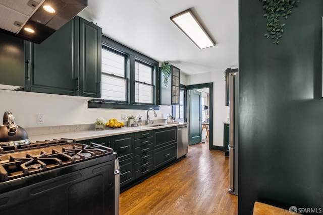 831 45th Ave, San Francisco, CA 94121 - kitchen with black gas range, wall chimney range hood, light countertops, wood finished floors, and stainless steel dishwasher