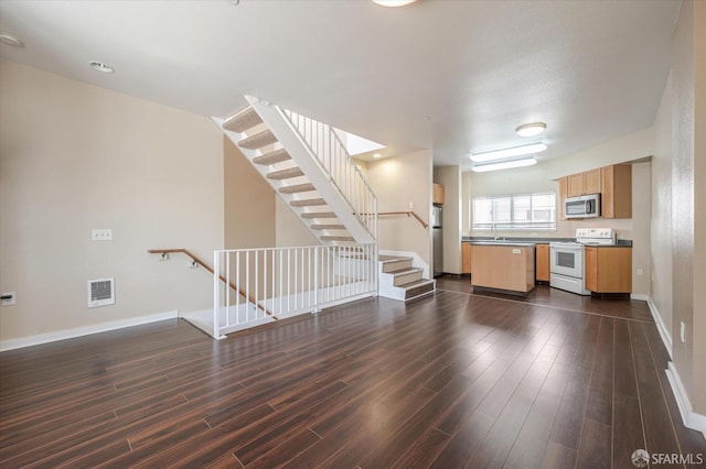 unfurnished living room featuring sink and dark wood-type flooring