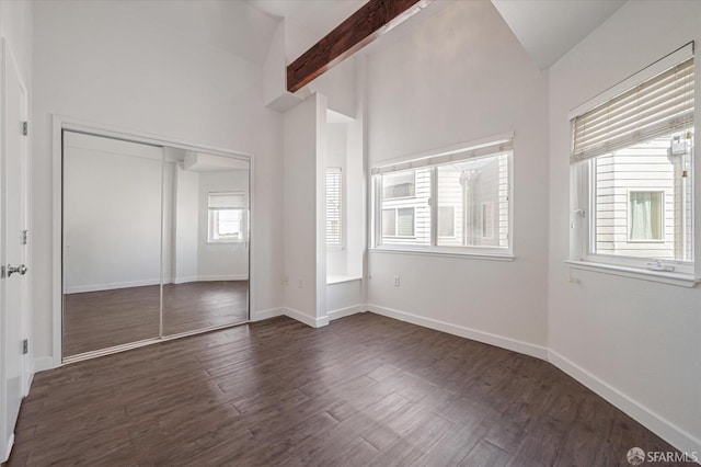 unfurnished bedroom featuring vaulted ceiling with beams, dark hardwood / wood-style flooring, and a closet