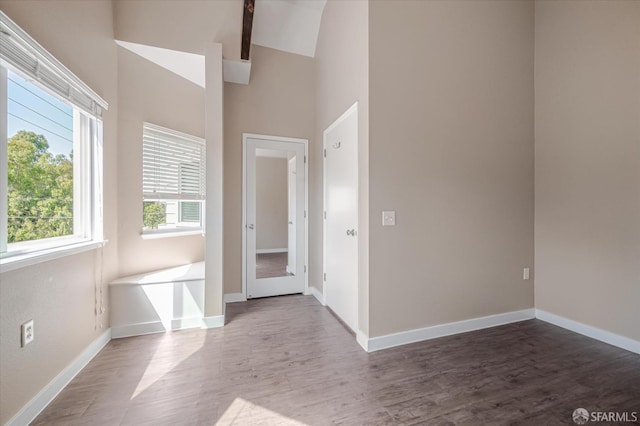 interior space featuring beam ceiling, dark hardwood / wood-style flooring, and high vaulted ceiling