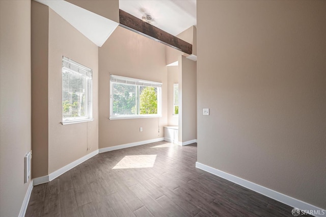 spare room featuring lofted ceiling with beams and dark wood-type flooring