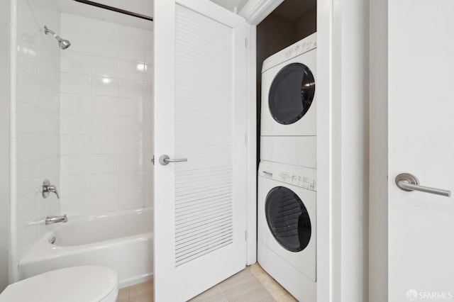 interior space with stacked washing maching and dryer, toilet, and tiled shower / bath