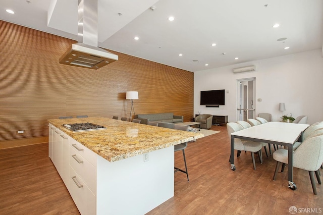 kitchen featuring white cabinetry, island exhaust hood, a kitchen island, and light wood-type flooring