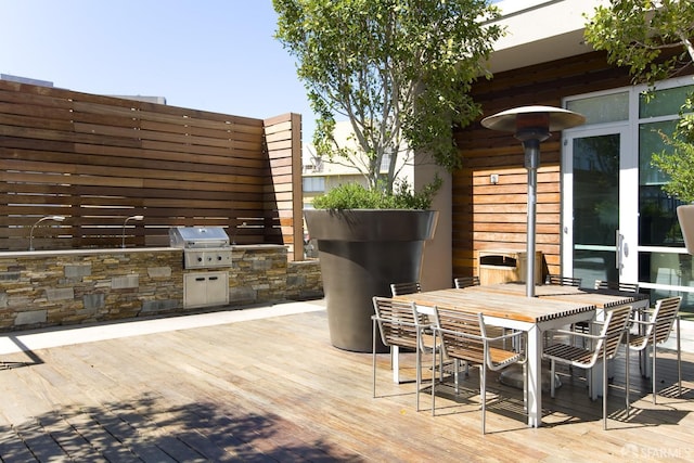 wooden terrace with french doors, a grill, and exterior kitchen