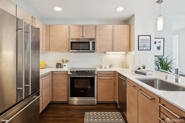 kitchen with dark hardwood / wood-style floors, light brown cabinetry, sink, hanging light fixtures, and stainless steel appliances