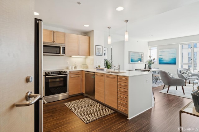 kitchen with pendant lighting, sink, dark wood-type flooring, appliances with stainless steel finishes, and kitchen peninsula