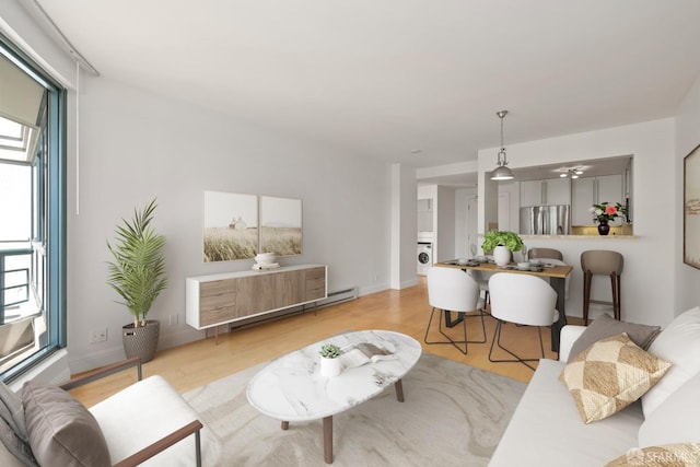living room featuring washer / clothes dryer, wood finished floors, baseboards, and baseboard heating