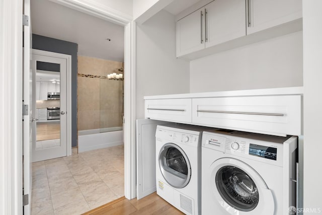 clothes washing area featuring cabinet space and separate washer and dryer