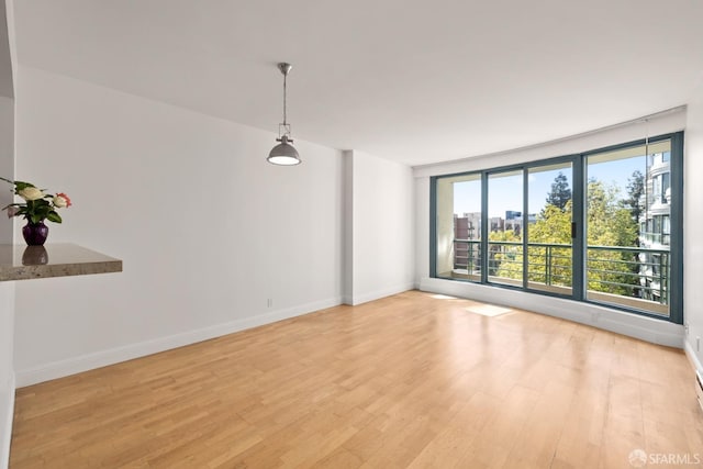 spare room featuring a view of city, light wood-style floors, and baseboards