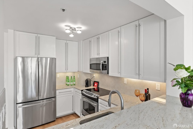 kitchen with light stone counters, white cabinetry, and stainless steel appliances