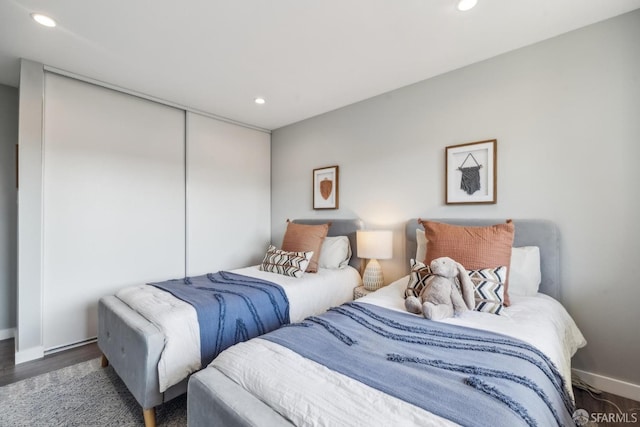 bedroom with wood finished floors, recessed lighting, a closet, and baseboards