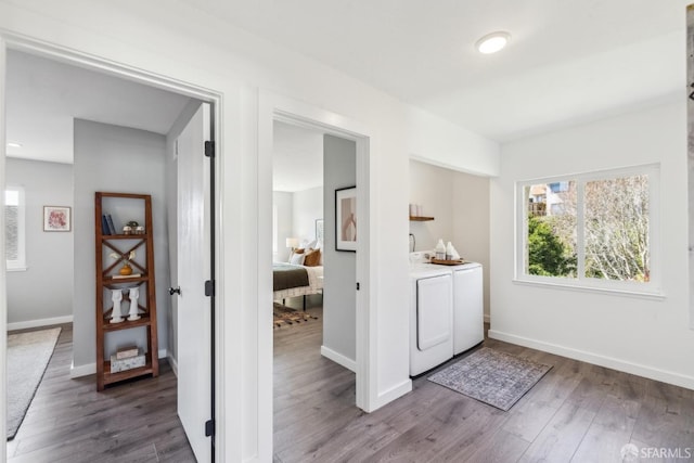 clothes washing area featuring wood finished floors, washing machine and dryer, baseboards, and laundry area