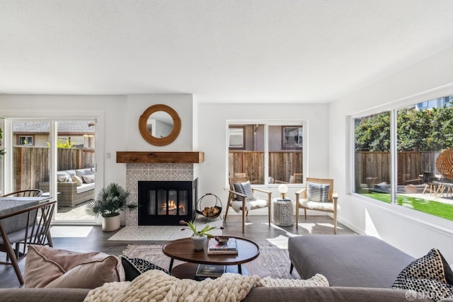 living area with wood finished floors, a wealth of natural light, and a tile fireplace