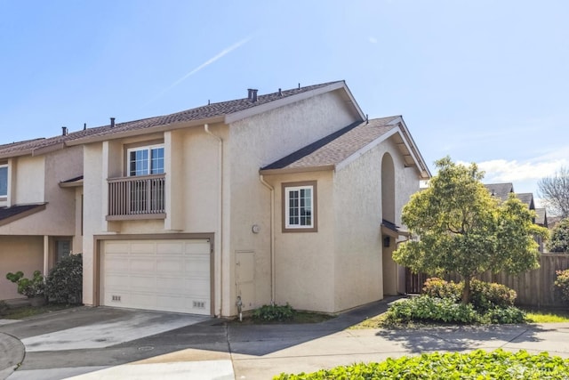 multi unit property featuring stucco siding, a garage, driveway, and fence