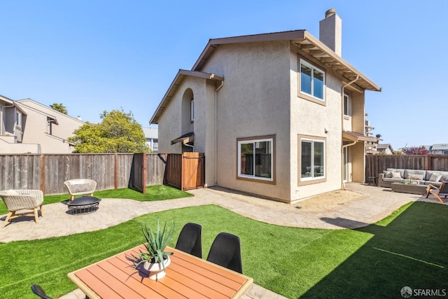 back of house featuring stucco siding, a fenced backyard, an outdoor living space with a fire pit, a chimney, and a patio area