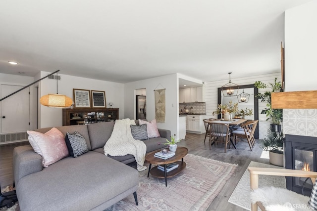 living room featuring visible vents, a glass covered fireplace, wood finished floors, recessed lighting, and a chandelier