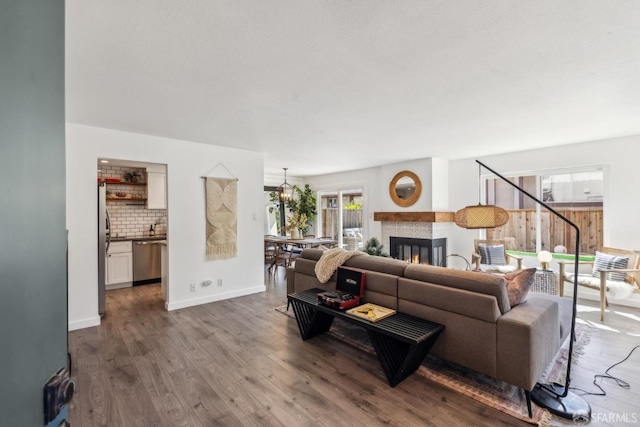 living area with a glass covered fireplace, baseboards, and wood finished floors