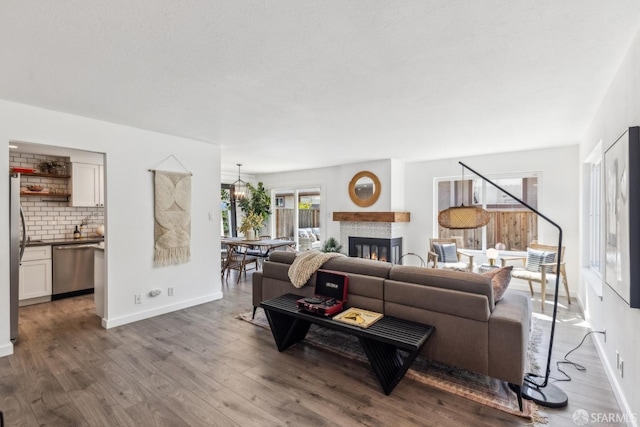 living area featuring a glass covered fireplace, wood finished floors, and baseboards