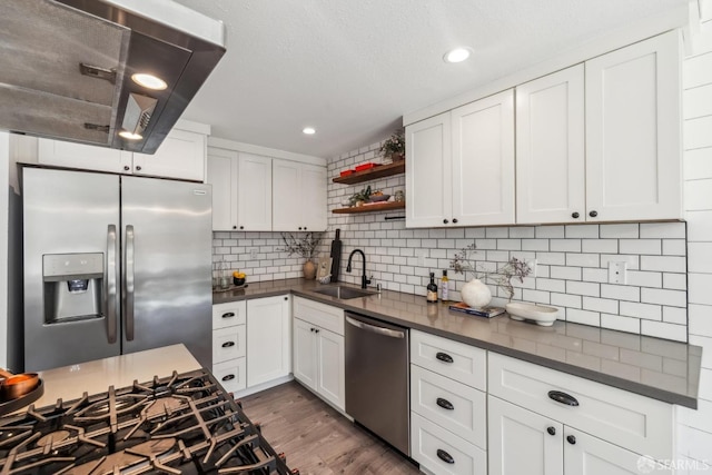 kitchen with dark countertops, open shelves, stainless steel appliances, and a sink