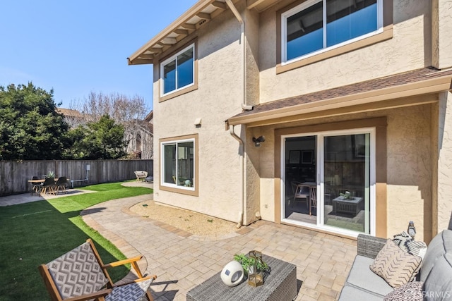 rear view of house featuring fence, stucco siding, an outdoor hangout area, a yard, and a patio area